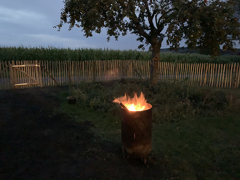 2912-2024 Staketenzaun mit Tor und Feuertonne am Abend