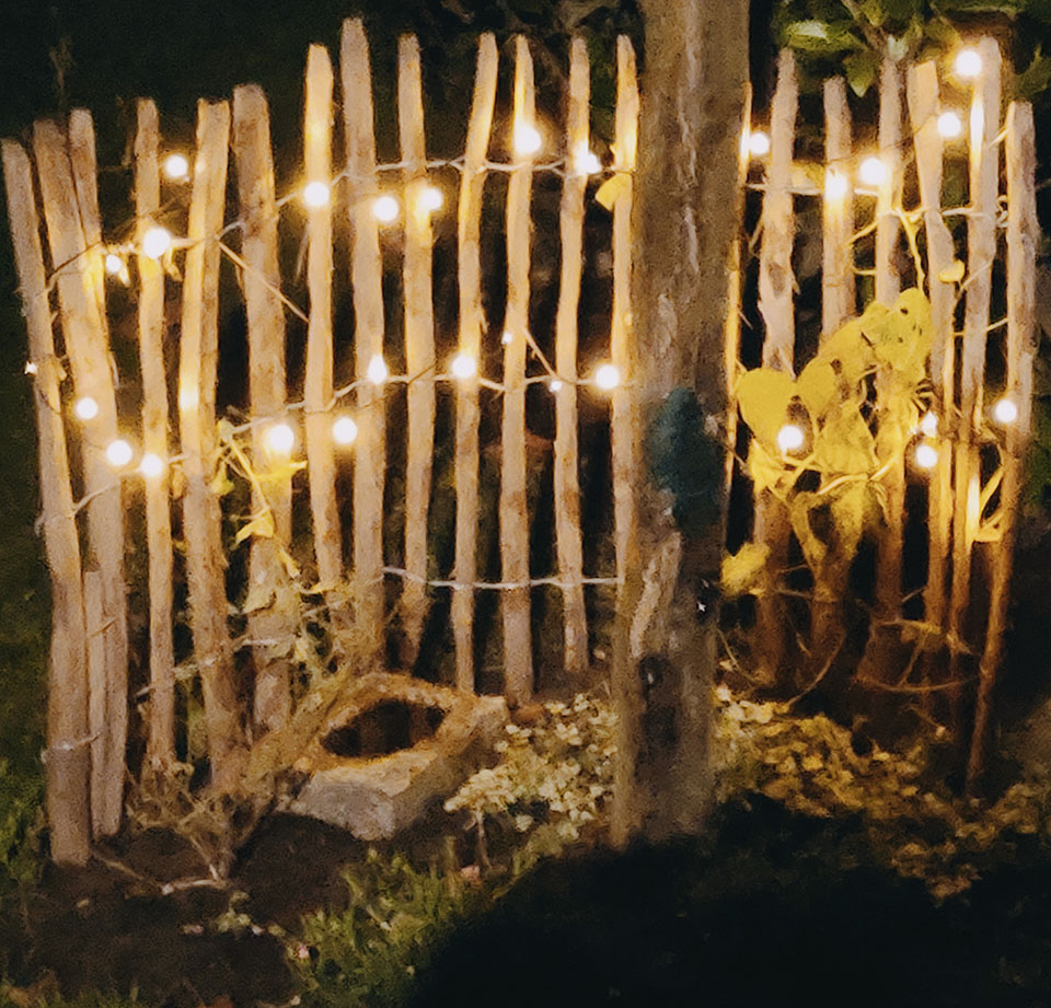 2711-2304 Staketenzaun bei Nacht mit Lichterkette